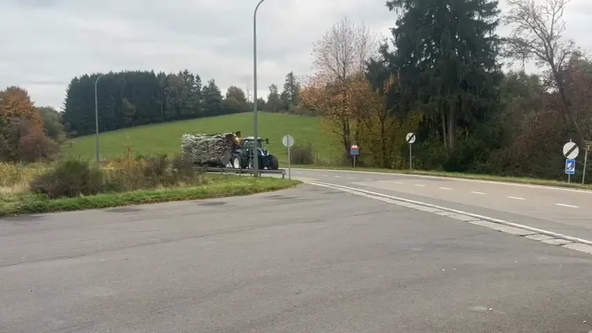 Trekker met beladen aanhanger steekt het kruispunt over.